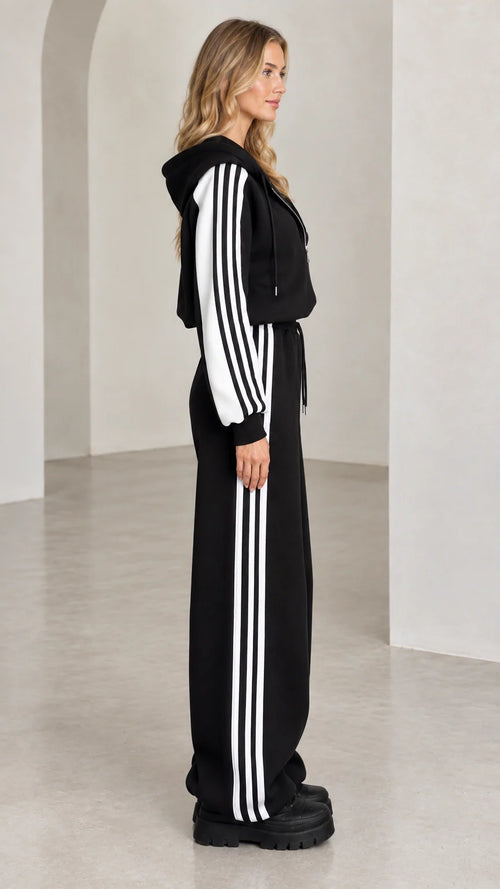 Side profile of model wearing black two-piece striped track set
