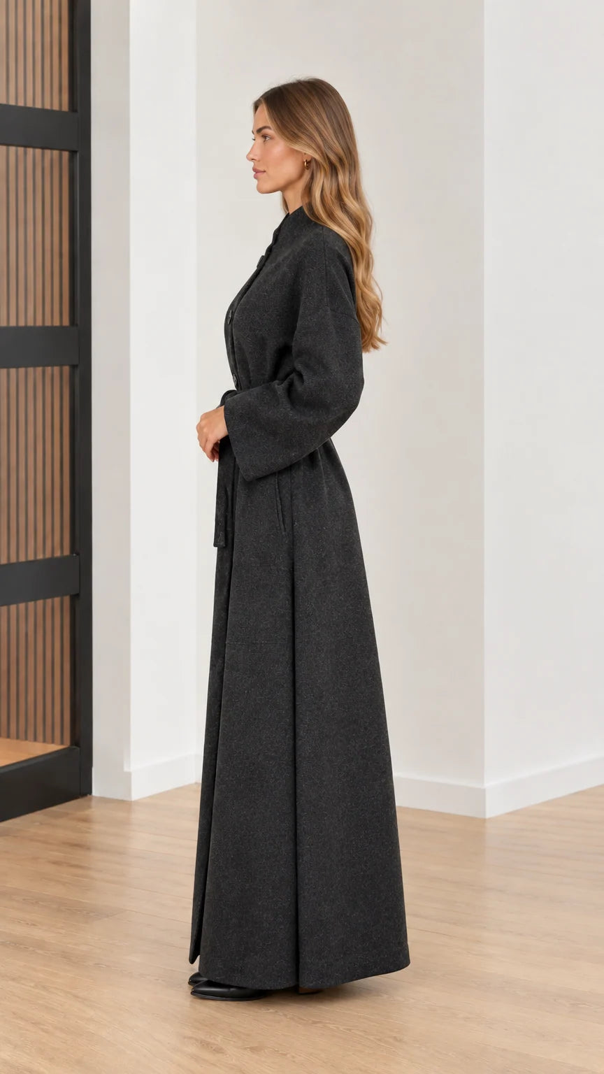 Side profile view of woman in long charcoal grey wool-look overcoat
