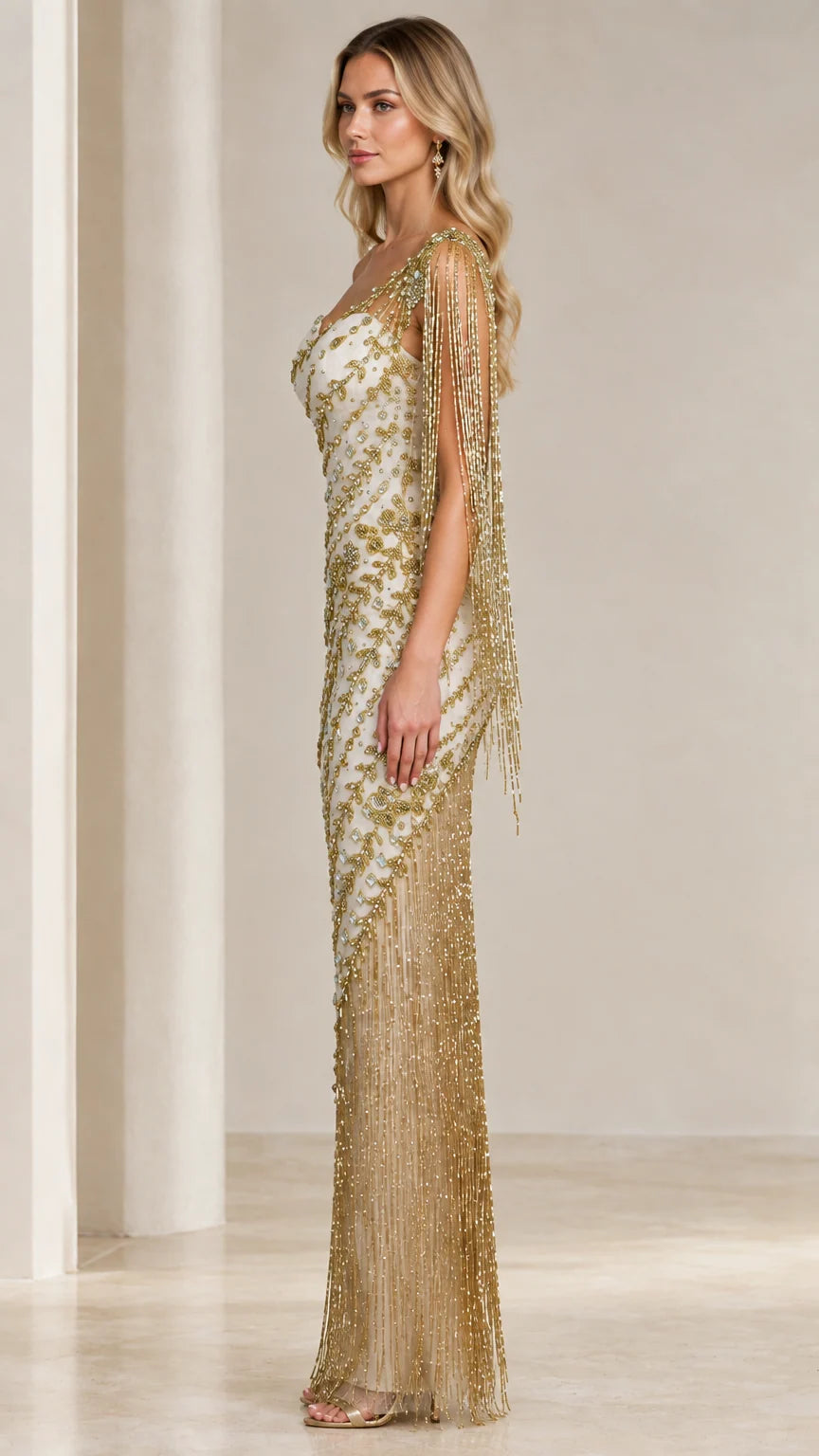 Side profile of model in Ivory Gold one-shoulder embellished gown showing shoulder fringe