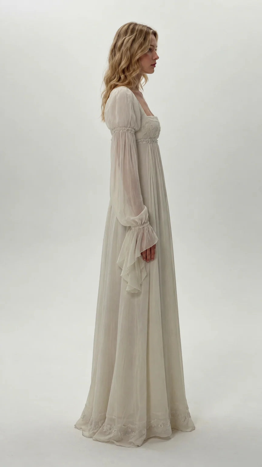 Side profile of model wearing ivory long bell sleeve empire waist dress
