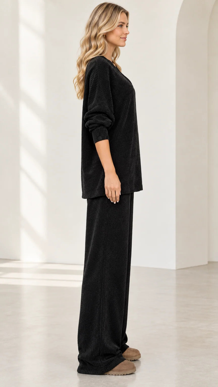 Side profile view of woman wearing black textured knit loungewear two piece set