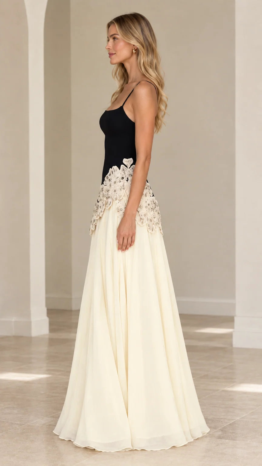 Side 3/4 view of black and cream maxi dress showing waistline embroidery and flowing skirt