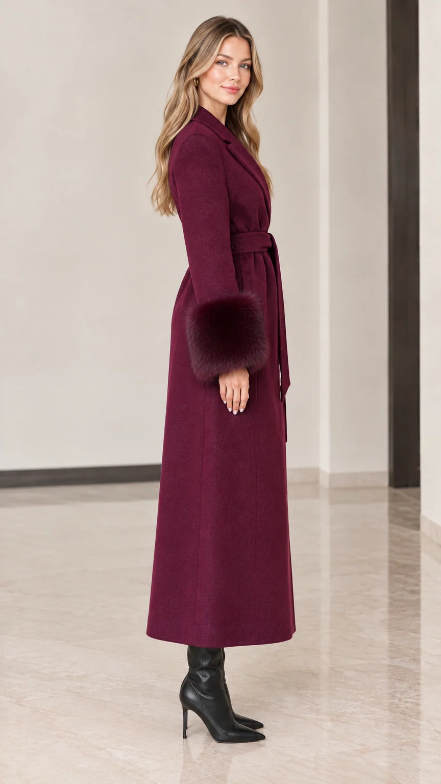 Side profile of model in burgundy floor-length belted winter coat with fur sleeve trims