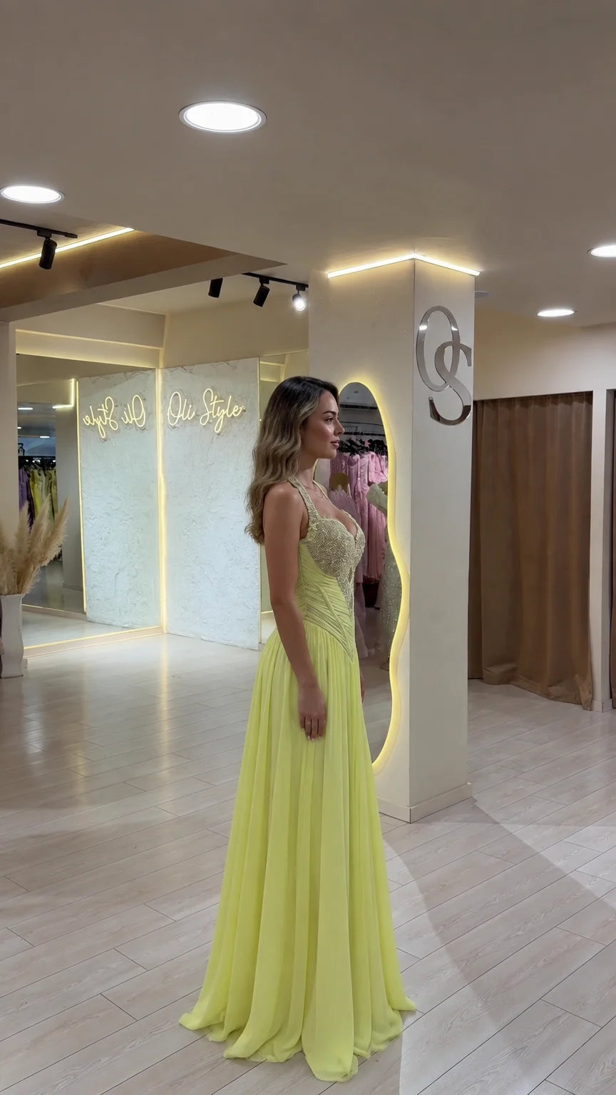 Side angle of model in pastel yellow beaded halter formal maxi dress