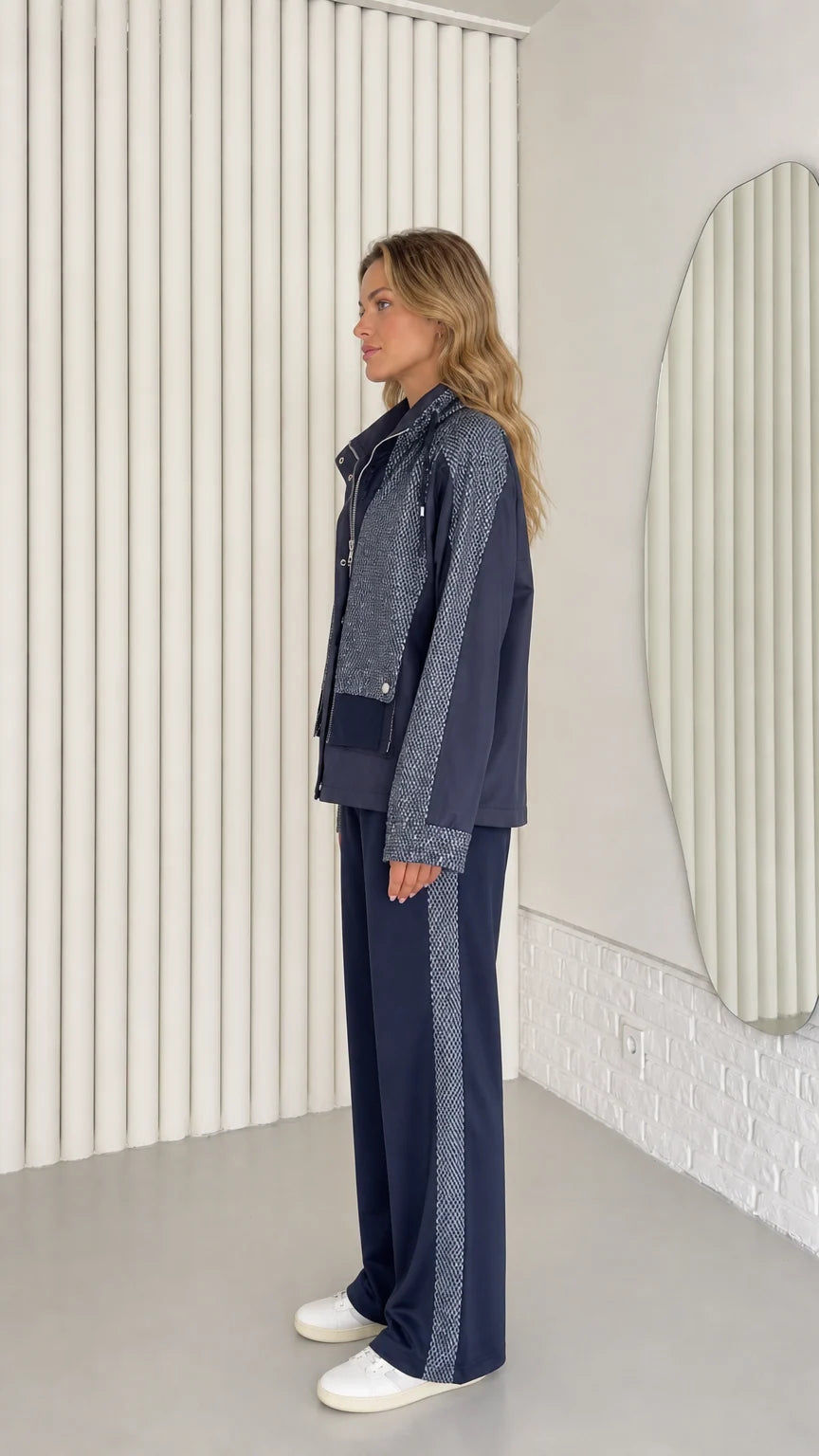Side profile view of woman wearing navy blue two-piece jacket and wide-leg tracksuit