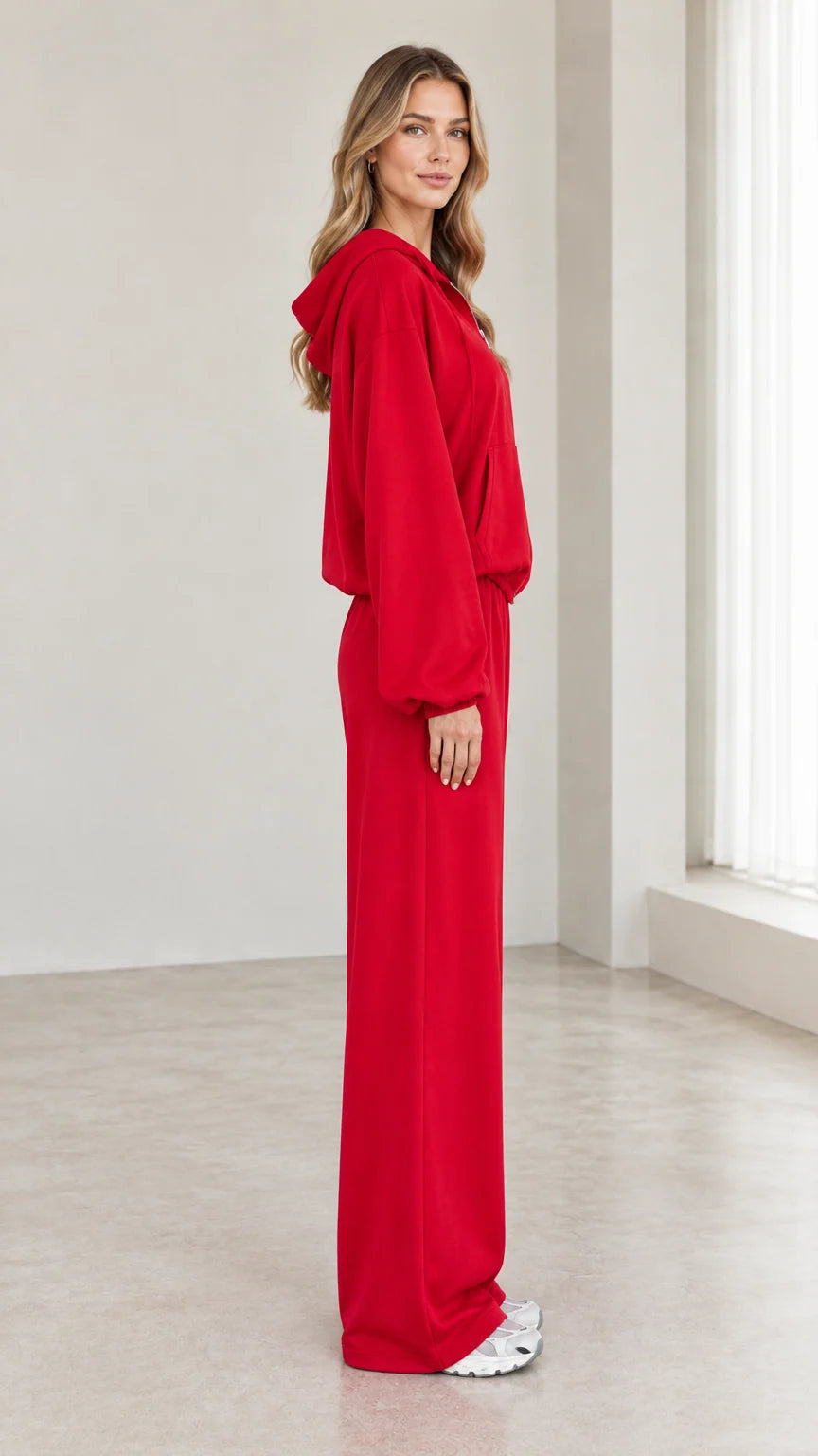 Side view of woman wearing red zip-up hoodie and matching wide-leg trousers