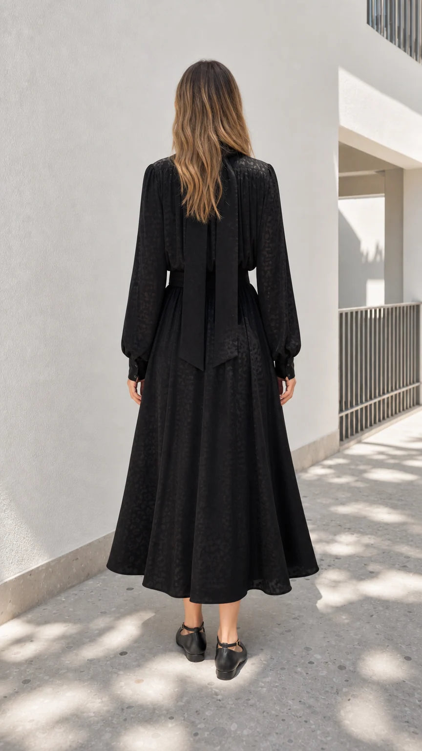 Model wearing black midi dress showing back bow detail