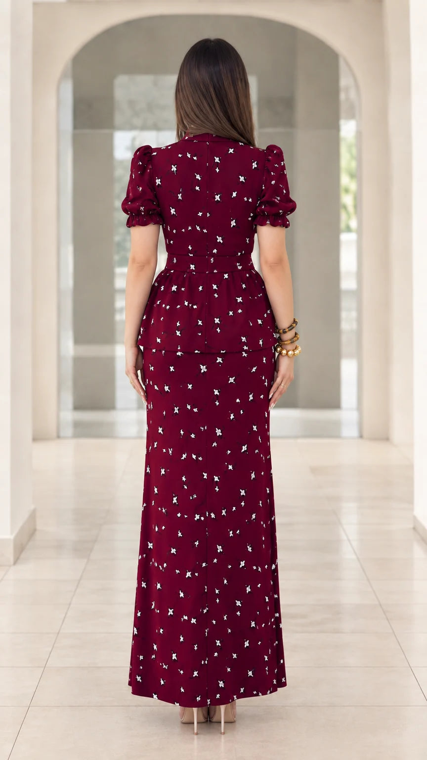 Back view of model wearing burgundy floral peplum maxi dress showing fitted silhouette