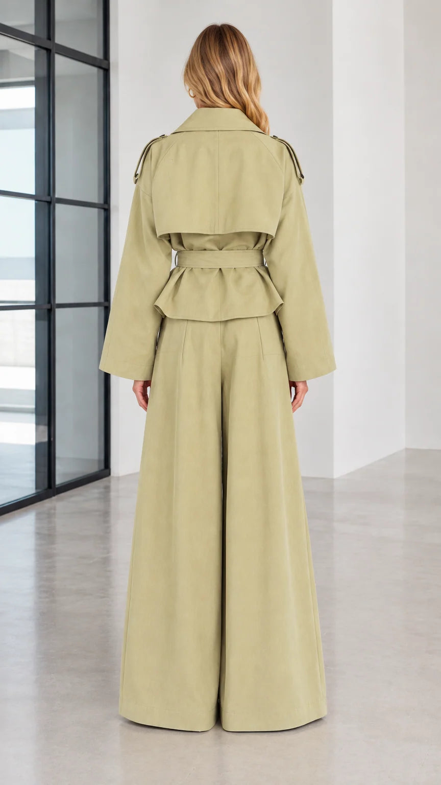 Back view of woman wearing sage green trench jacket with back flap and wide-leg trousers