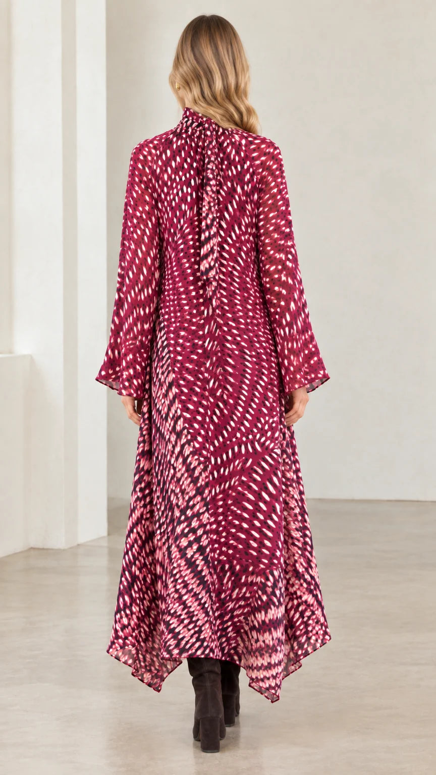 Back view of model in magenta abstract print long sleeve handkerchief maxi dress