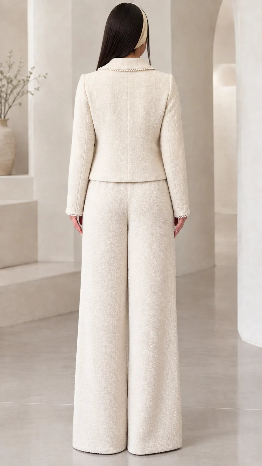 Back view of model wearing the cream structured tweed jacket and floor-length wide-leg trousers