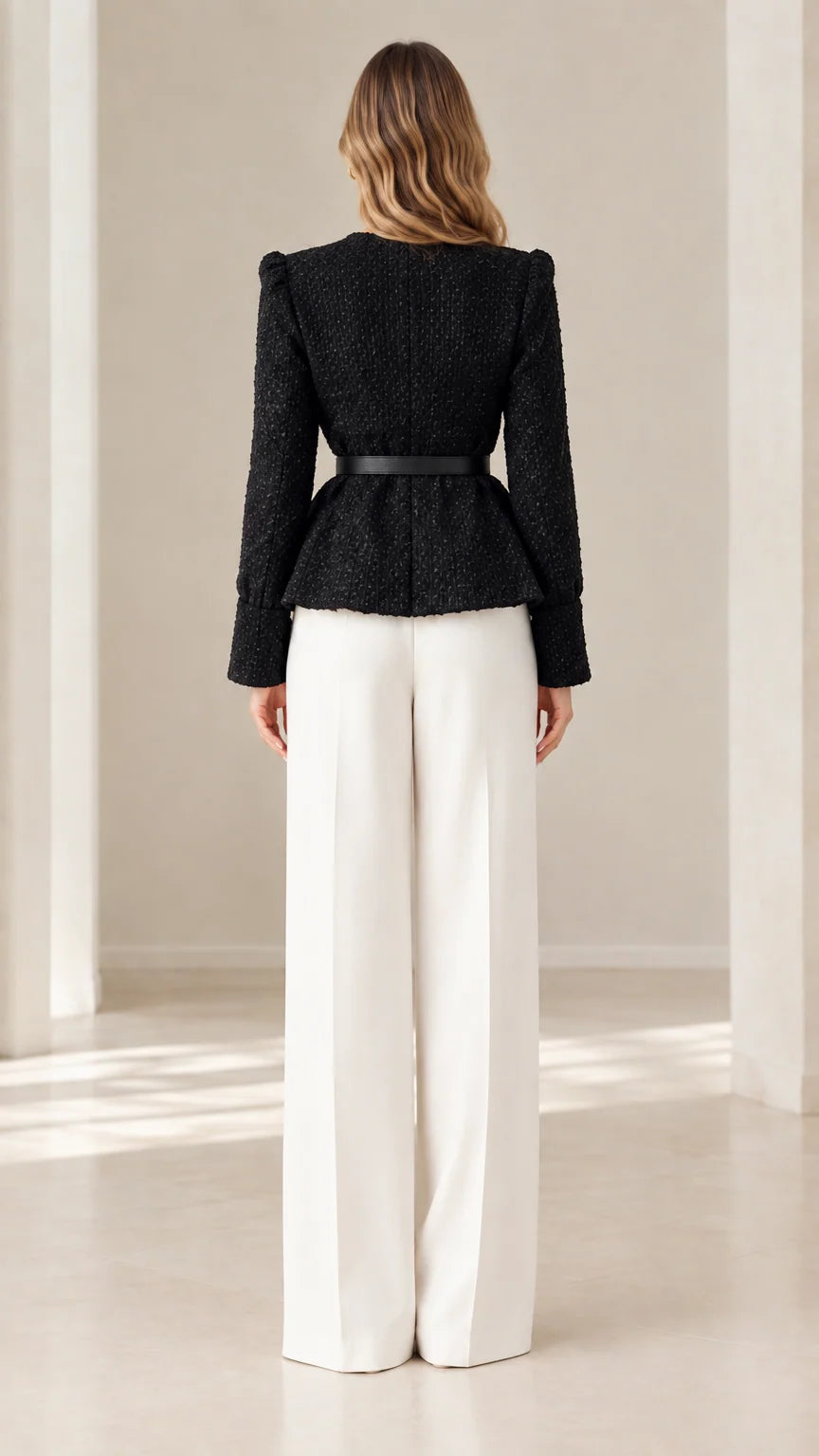 Back view of model in black collarless tweed peplum jacket and white wide-leg pants