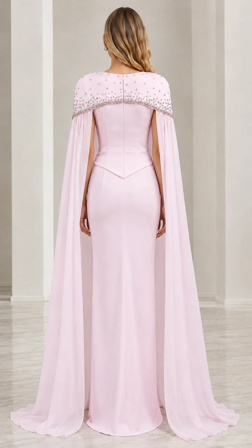 Back view of model in blush pink formal gown with long cape overlay