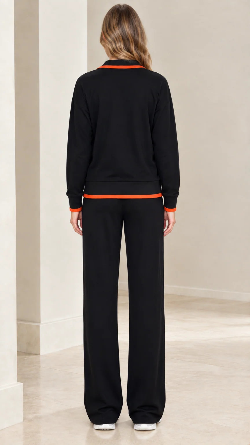 Back view of model wearing black zip-up tracksuit set