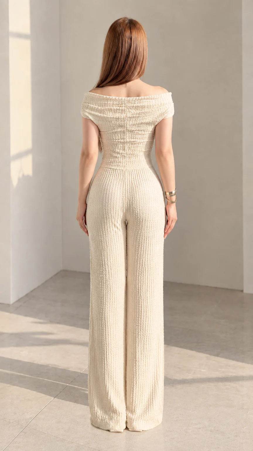 Back view of woman wearing cream textured off-shoulder top and wide-leg pants