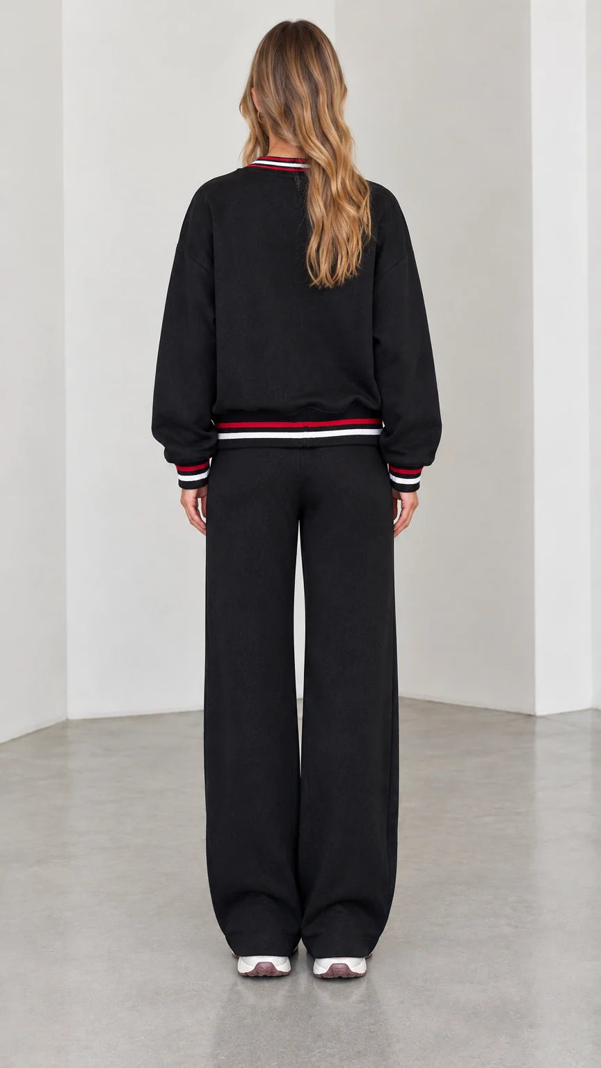 Back view of model wearing black zip-up lounge jacket and matching wide pants