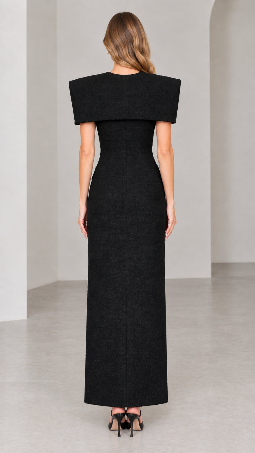 Back view of black tailored tweed maxi dress with structured shoulder cape