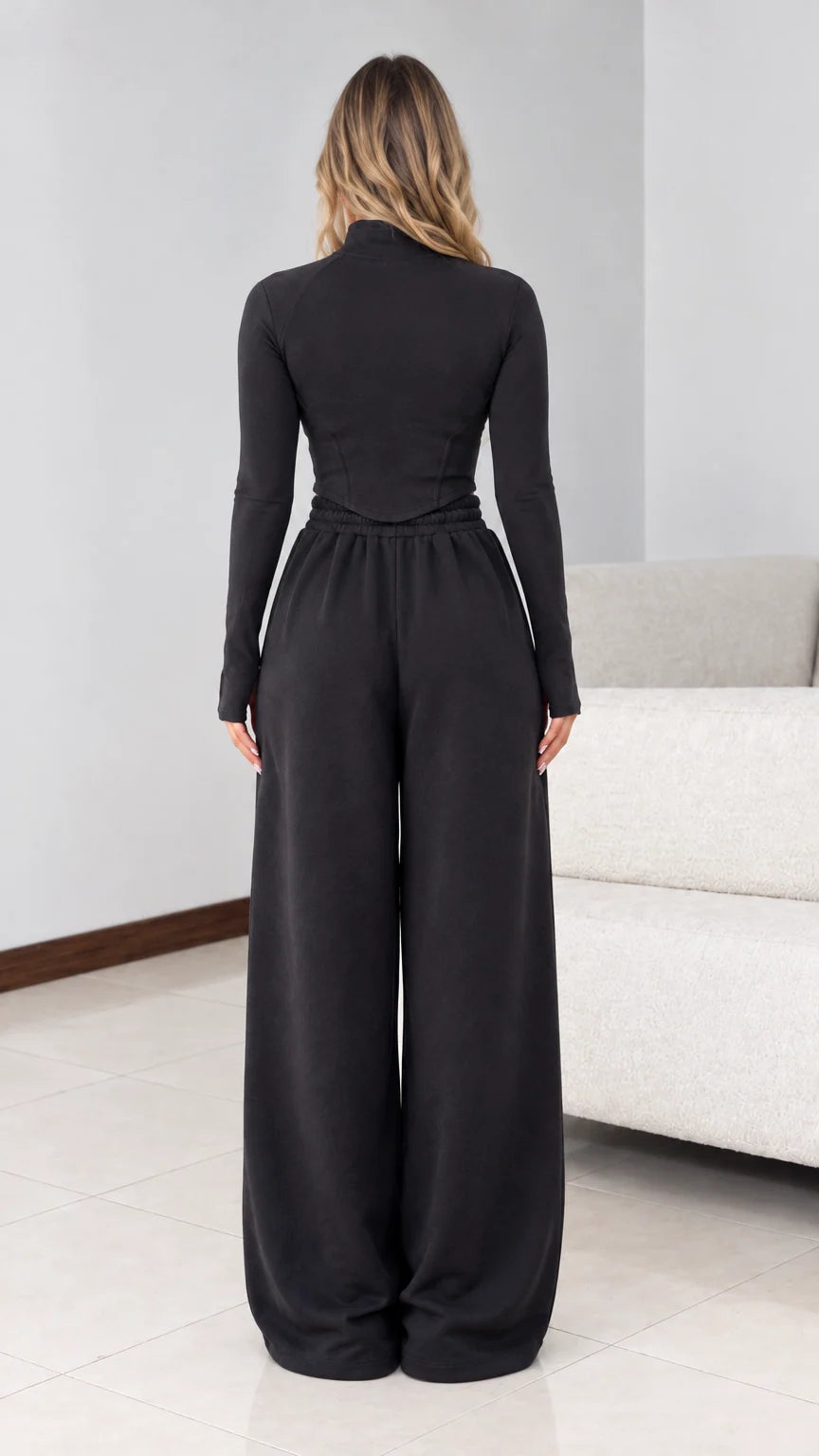 Back view of model wearing black half zip top and wide leg pants