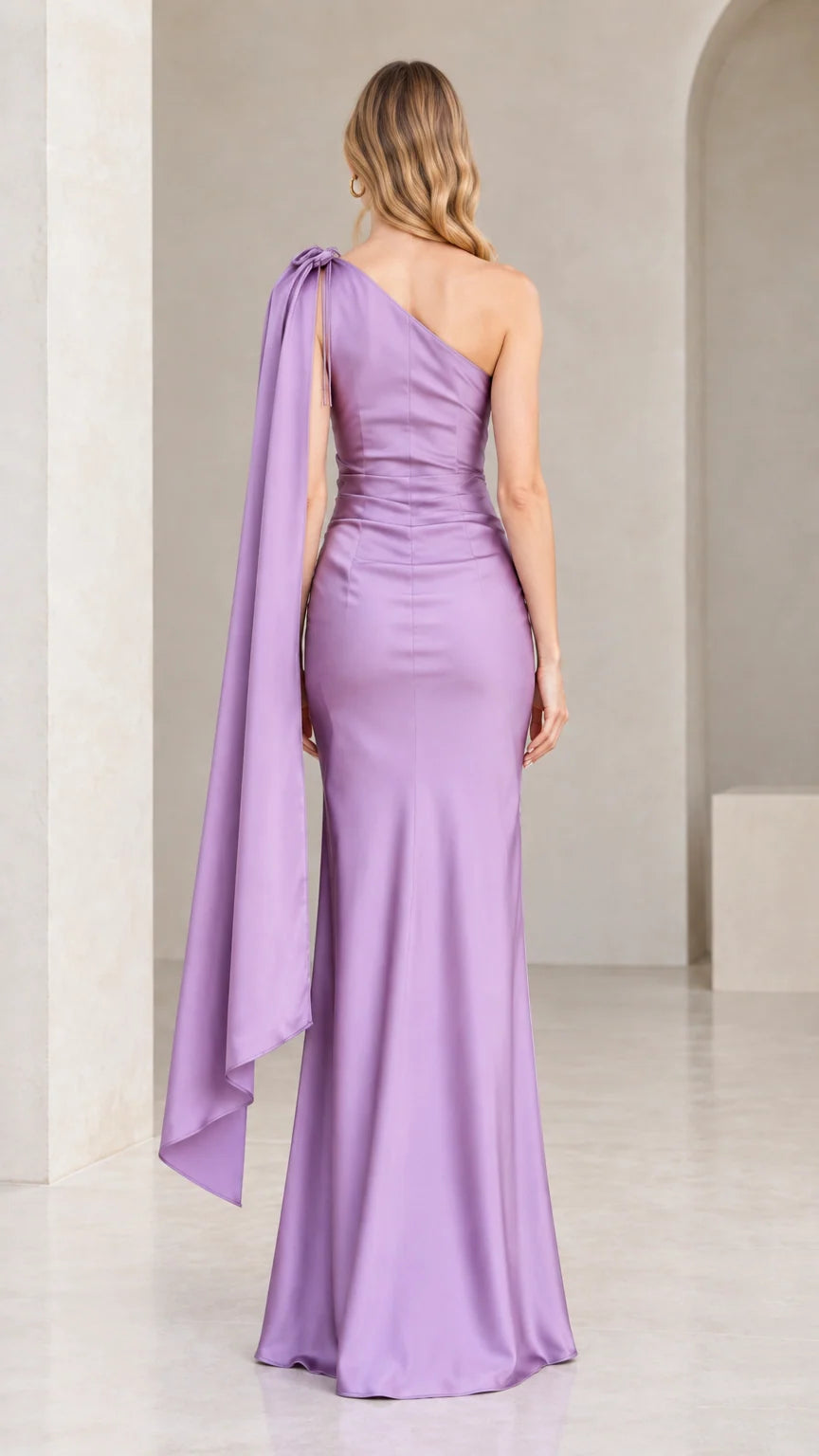 Back view of lavender one-shoulder evening gown highlighting the flowing capelet sash