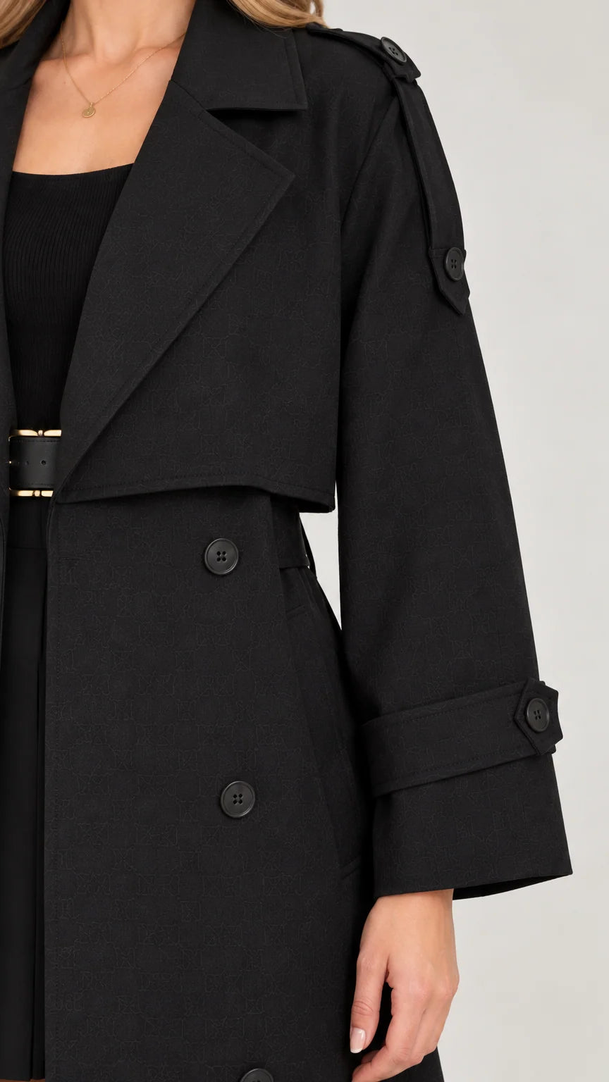 Close-up detail of wide lapel and shoulder tabs on black trench coat