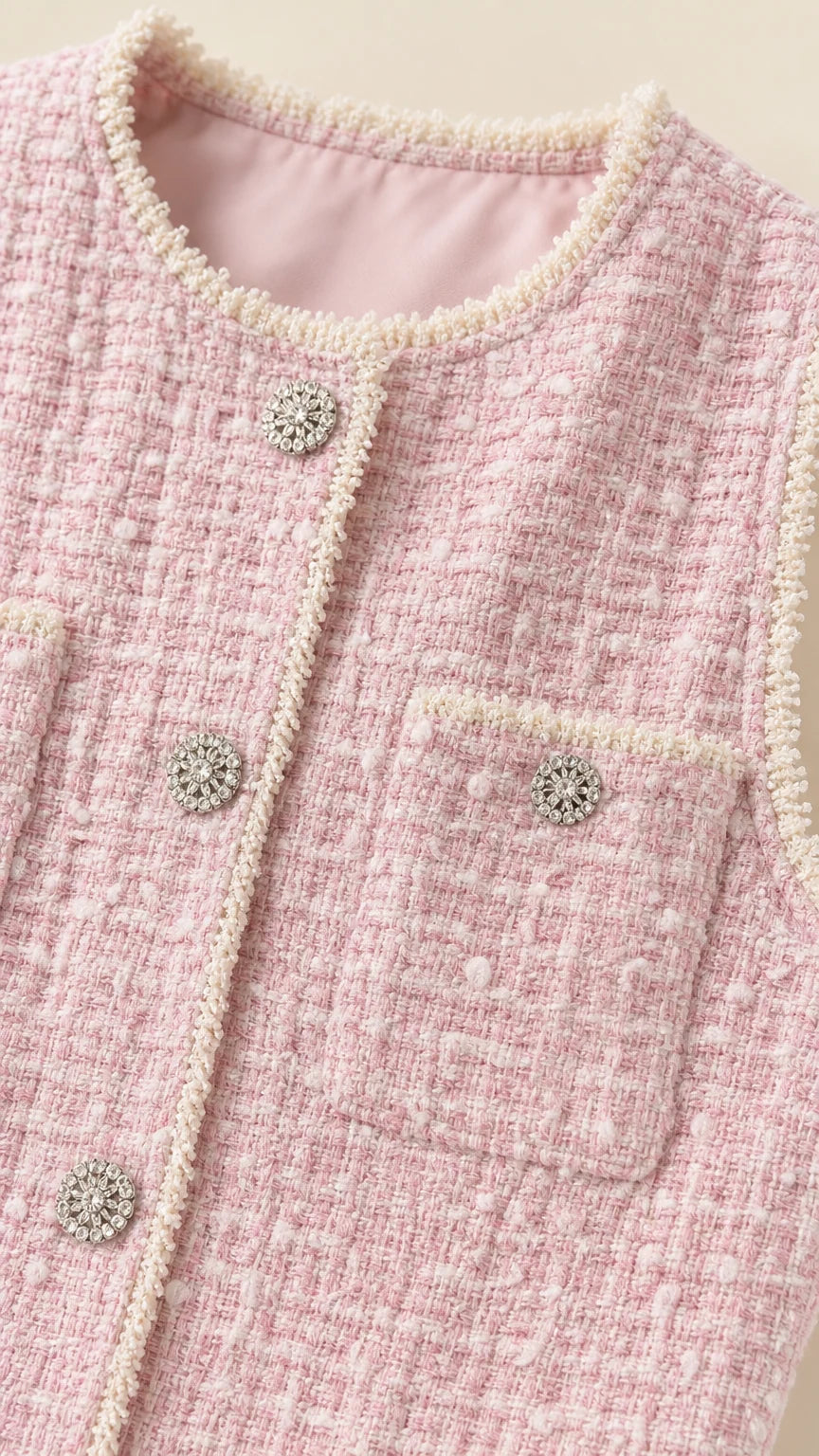 Close-up detail of pearl trim and jeweled buttons on pink tweed dress