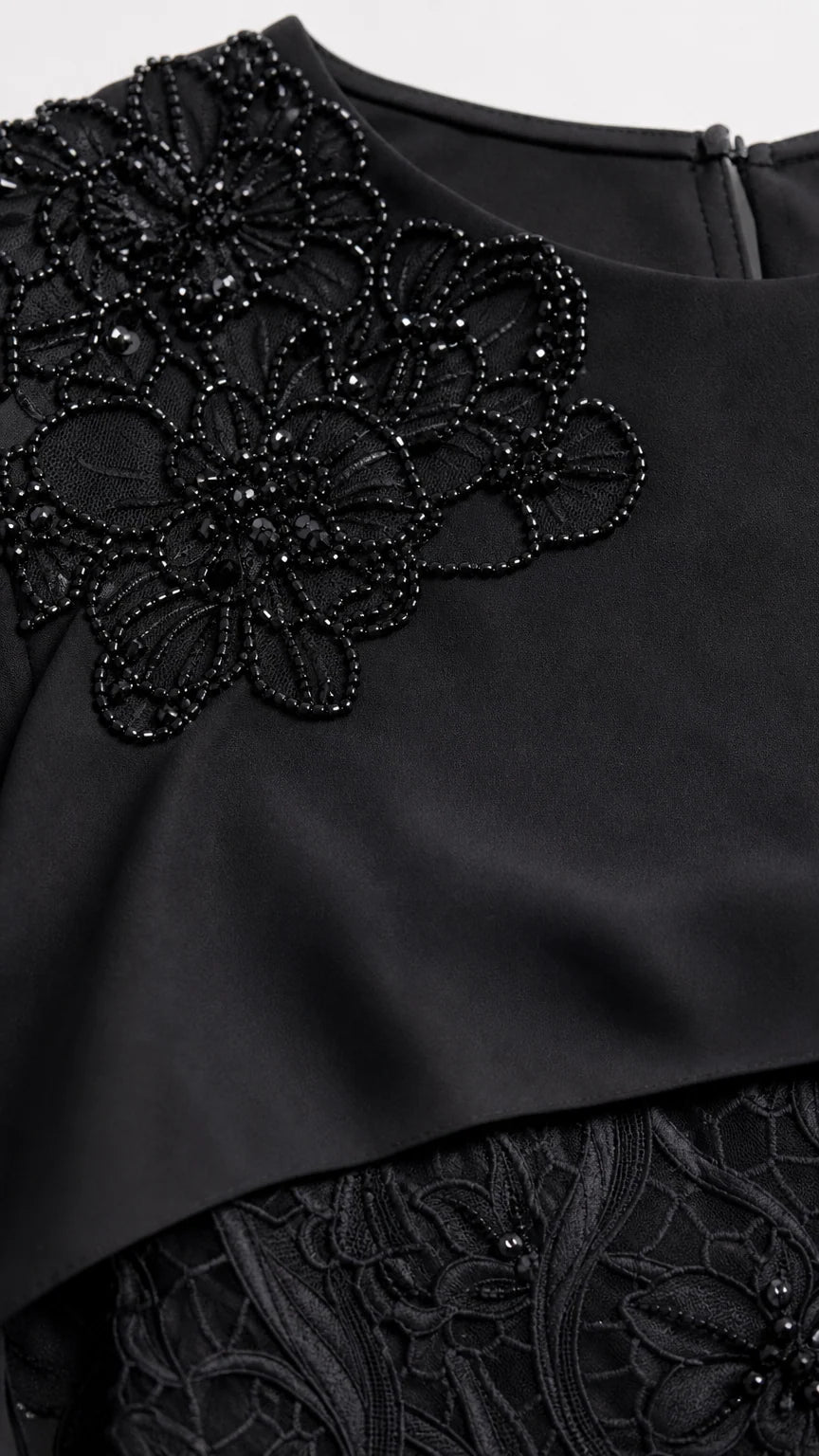 Close-up detail of floral beadwork embroidery on capelet neckline