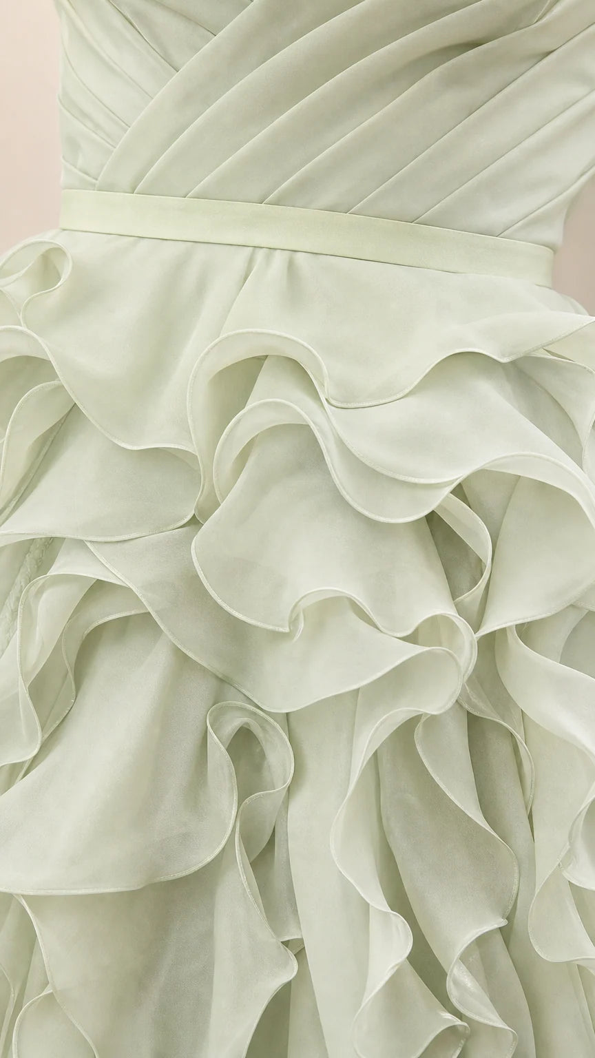 Close-up detail of structured waistband and cascading ruffles on sage green dress