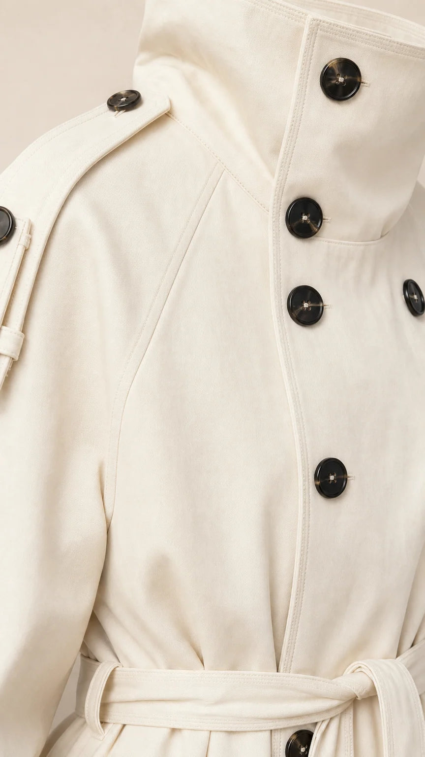 Close-up detail of Cream trench coat high buttoned stand collar and shoulder epaulets