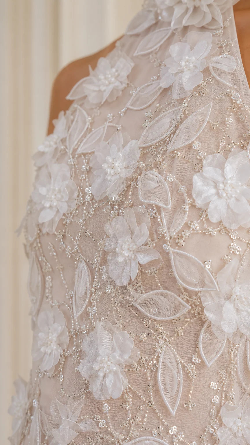 Close-up detail of 3D floral appliques and beaded embroidery on halter gown