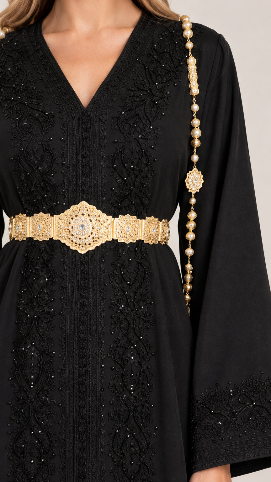 Close-up detail of black embroidered neckline and gold metallic belt