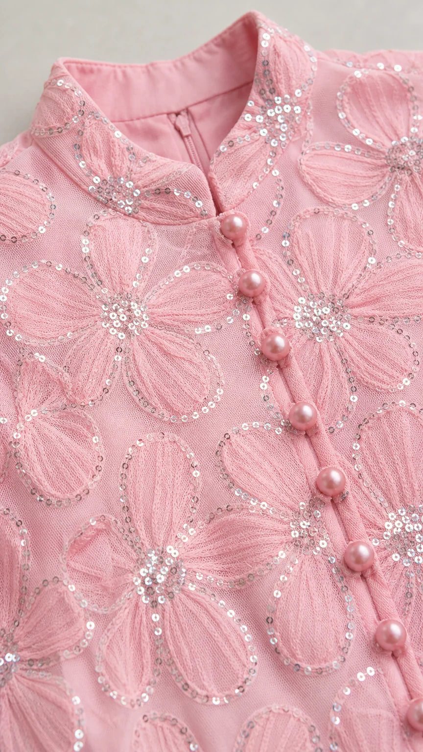 Close-up detail of mock neck, buttons, and sequin floral embroidery