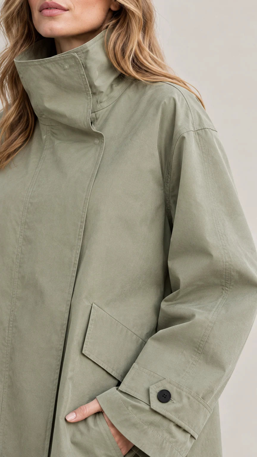 Close-up detail of high funnel collar, concealed placket, and flap pocket on Sage Green jacket