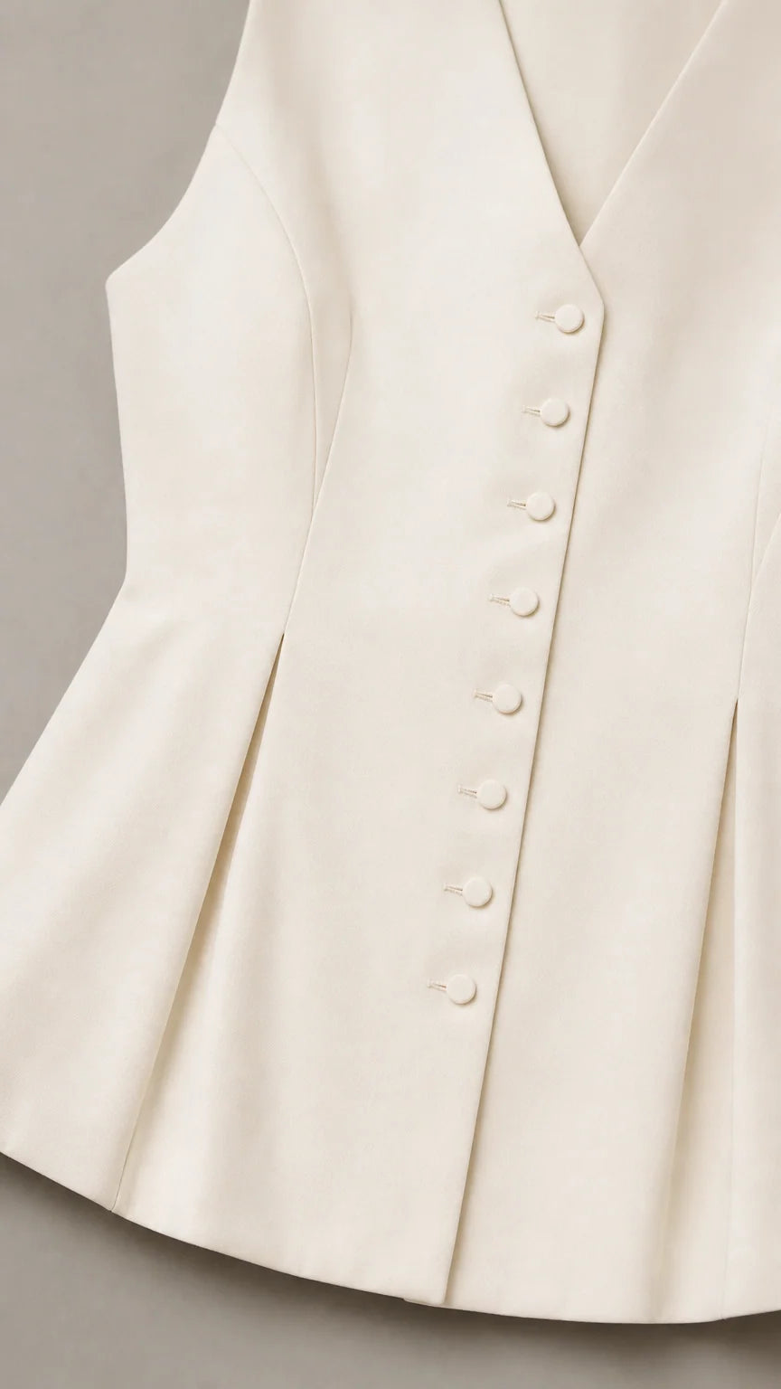 Close up of white vest button details and peplum hem