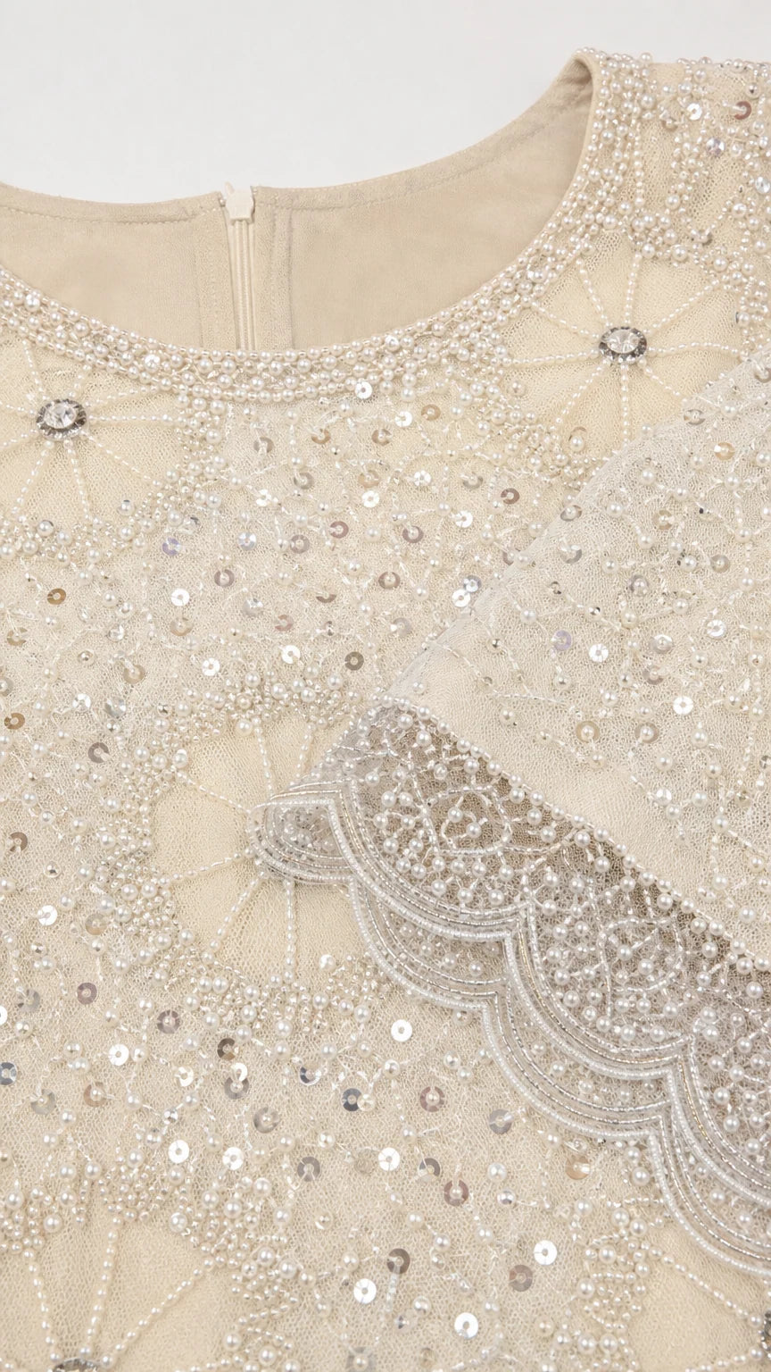 Close-up detail of intricate beading, sequins, and scalloped trim on Champagne neckline and cuff
