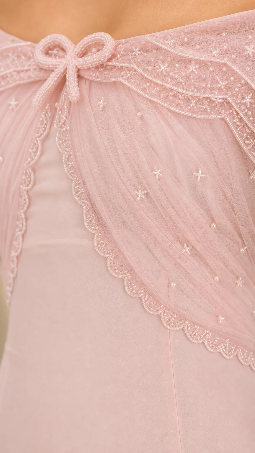 Close-up detail of embroidered sheer capelet with bead accents and bow