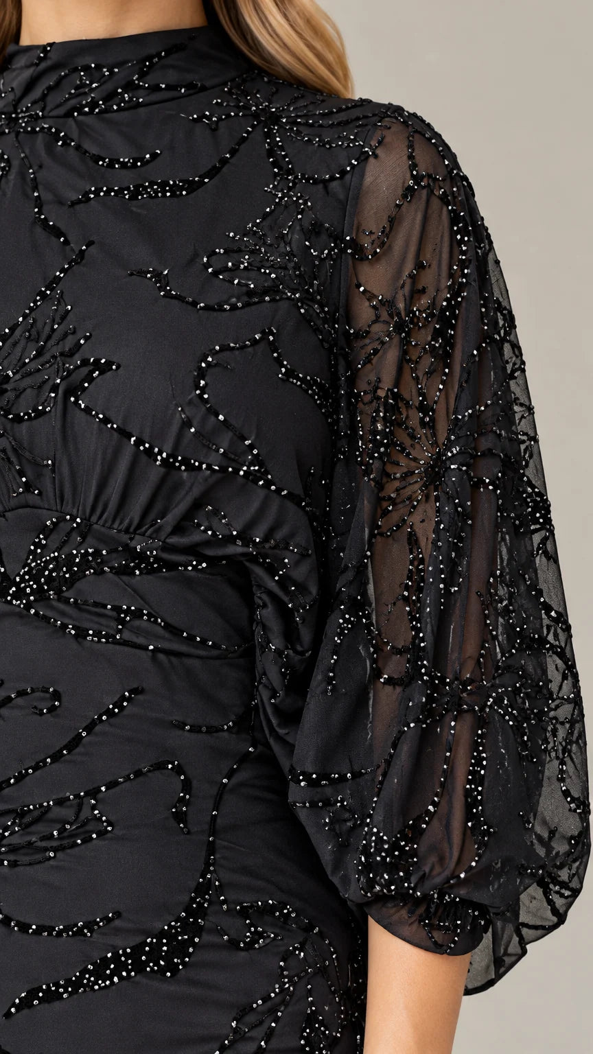 Close-up detail of sheer beaded sleeve and mock neckline craftsmanship