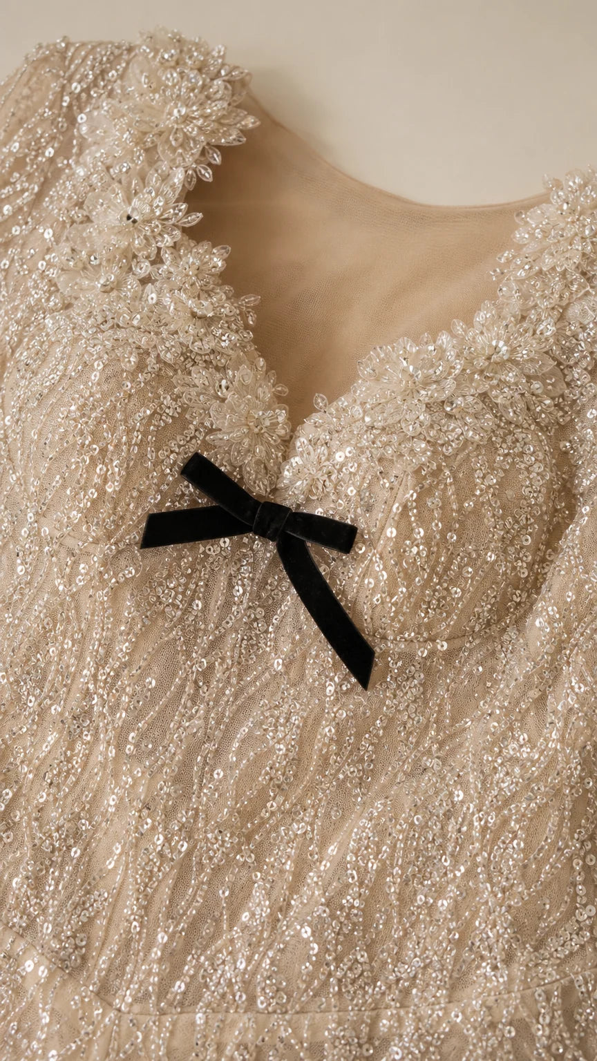 Close-up detail of scalloped sweetheart neckline with delicate black bow and sequin embroidery