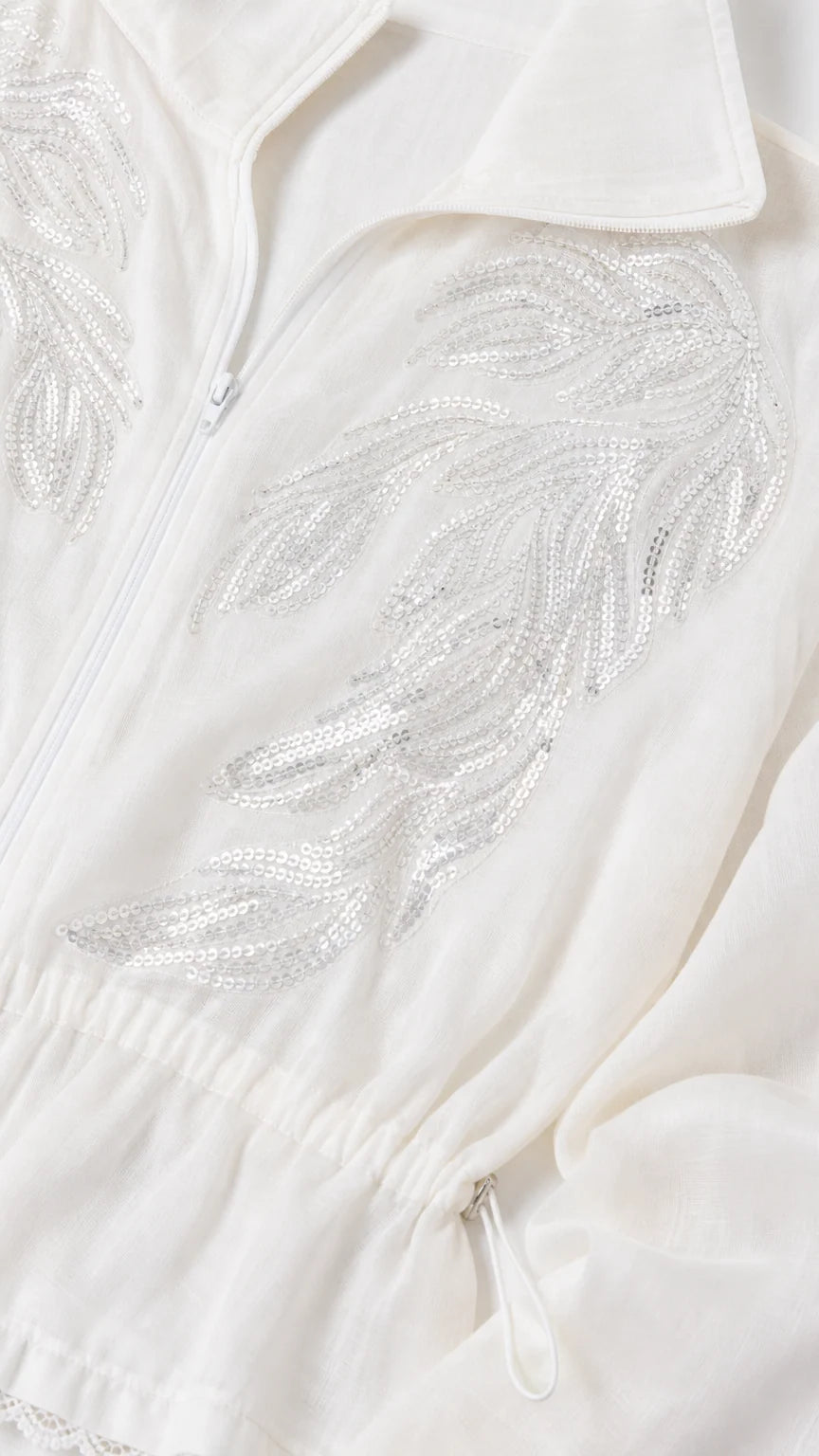 Close-up of intricate silver sequin leaf embroidery on white zip-up jacket