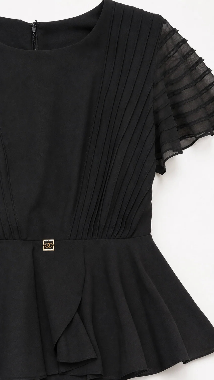 Close-up detail of pleated bodice and peplum accent on black dress