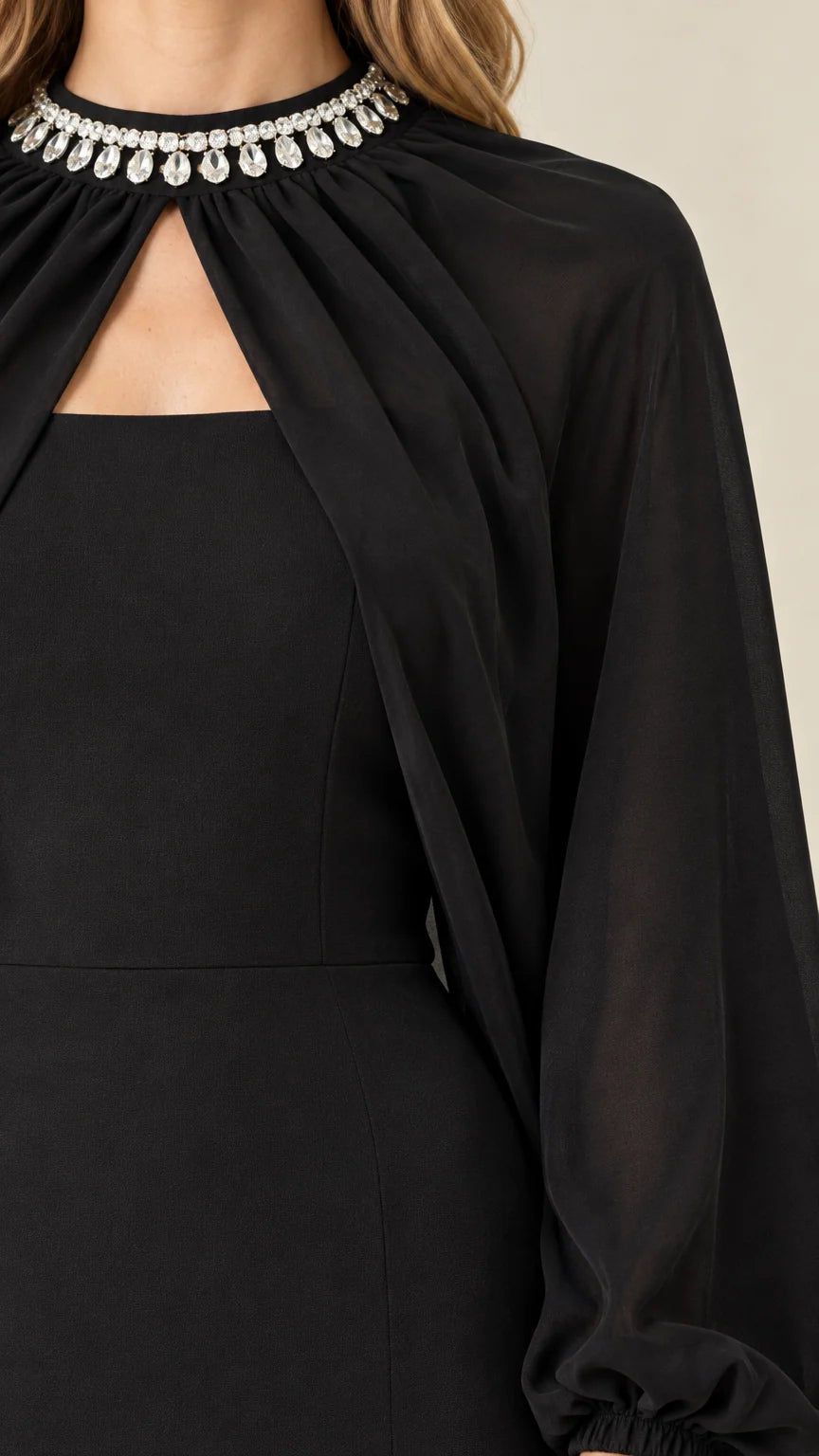 Close-up detail of rhinestone embellished collar and sheer cape on black evening gown