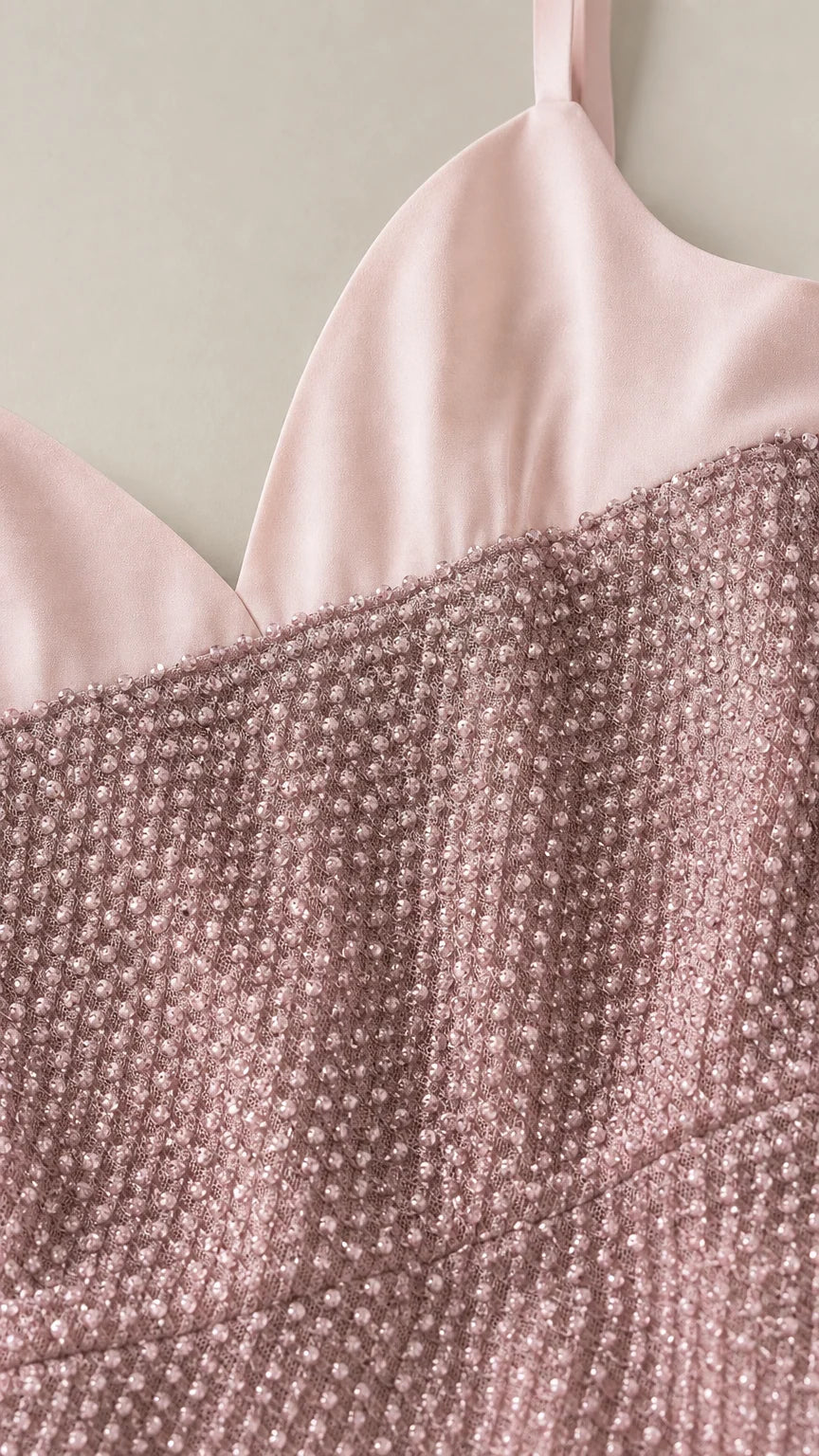 Close-up detail of smooth satin-finish neckline and textured shimmer fabric in dusty rose