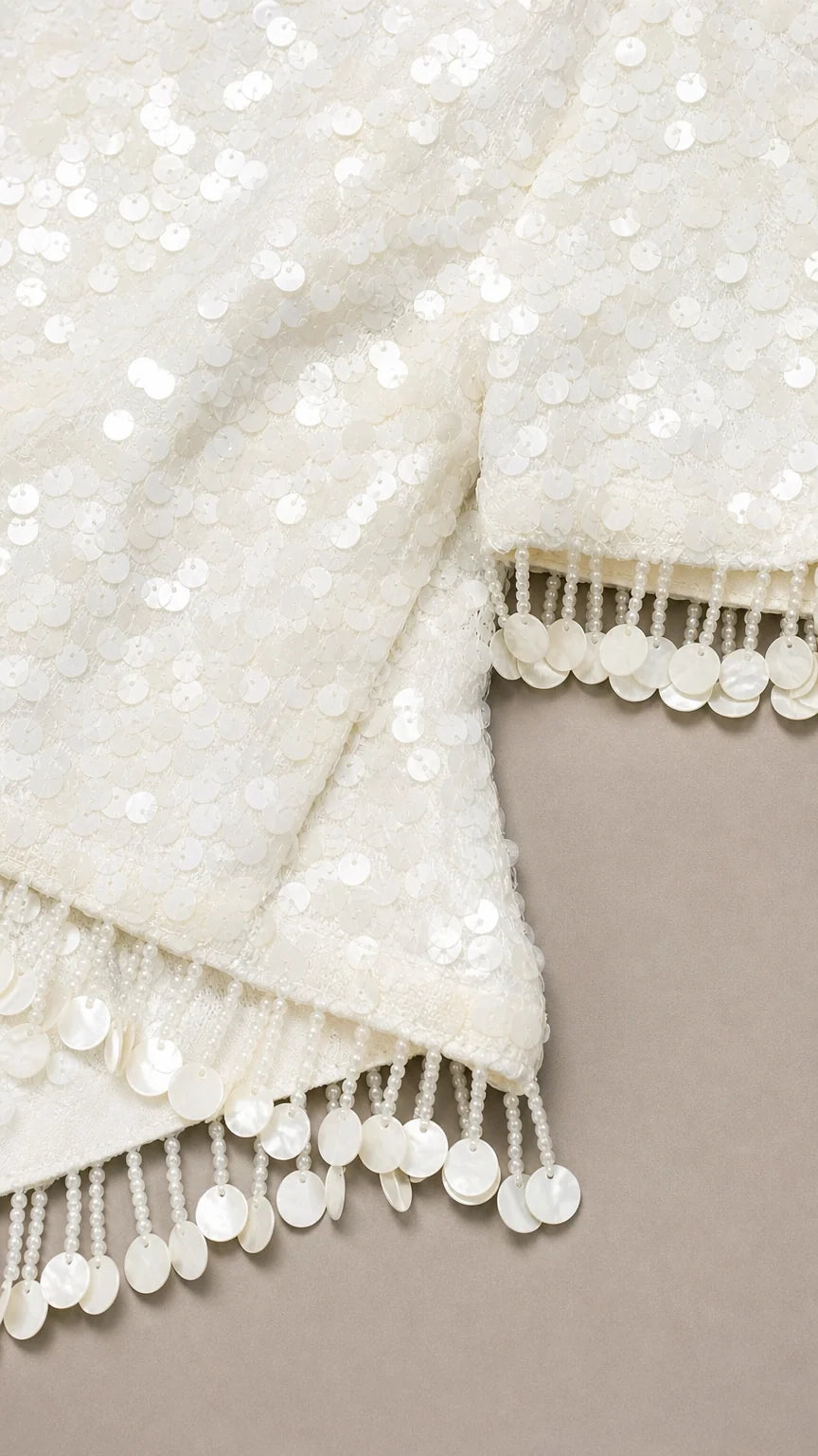Close-up of white sequin fabric and fringe trim
