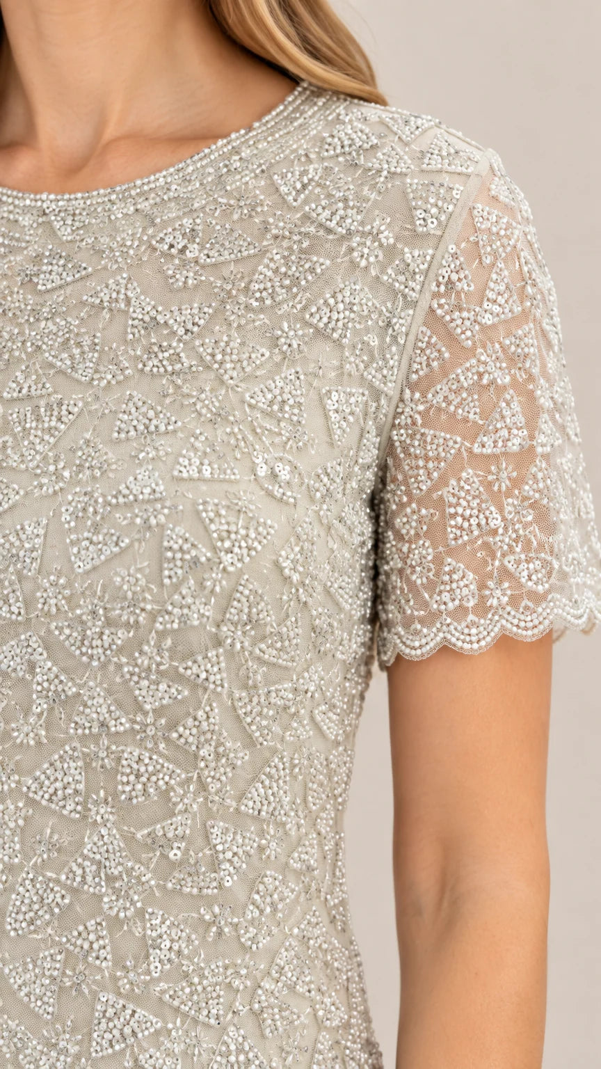 Close-up detail of intricate beading and scalloped sleeve hem on silver evening bodice