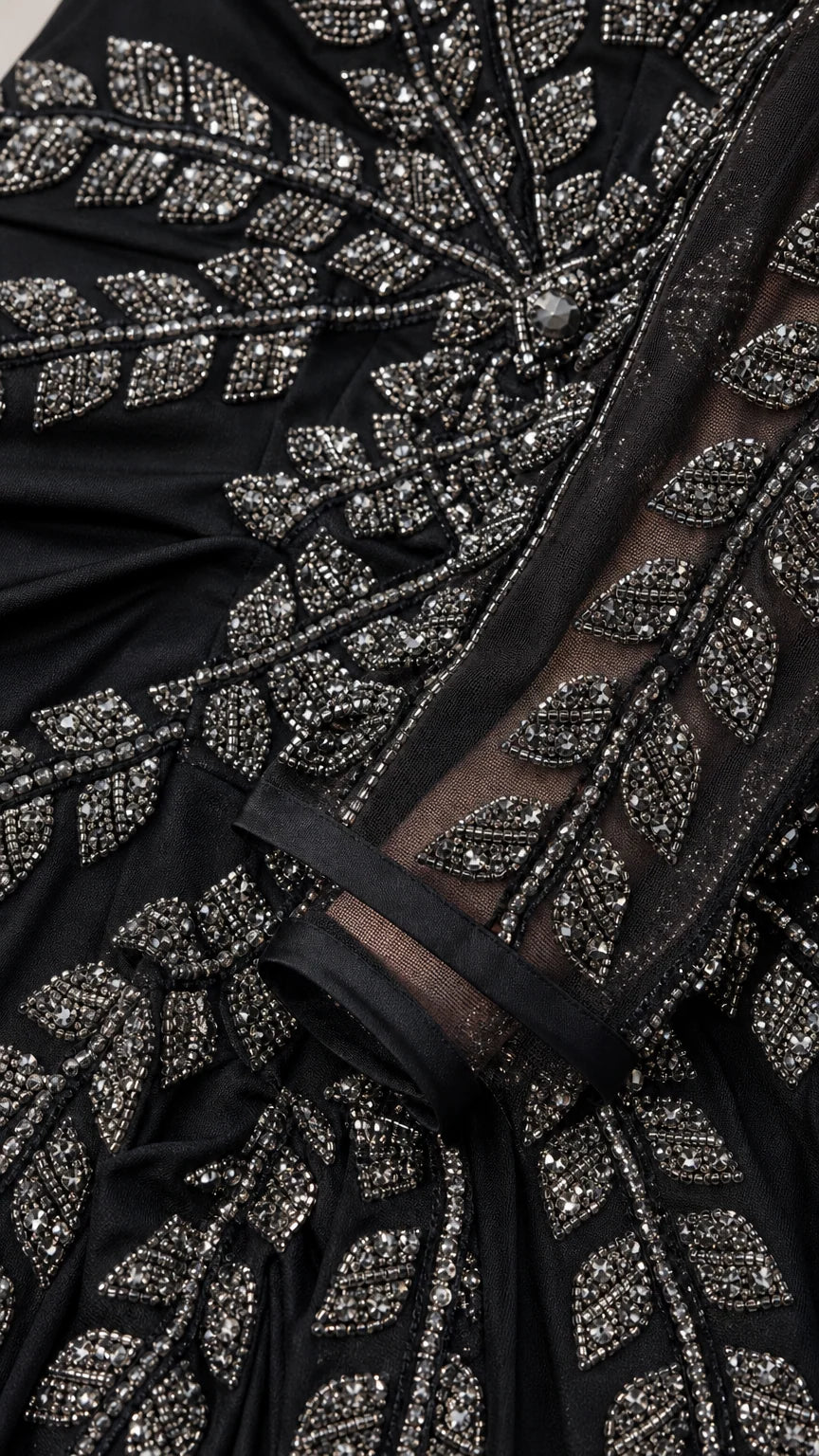 Close up of intricate metallic leaf beadwork on black evening gown