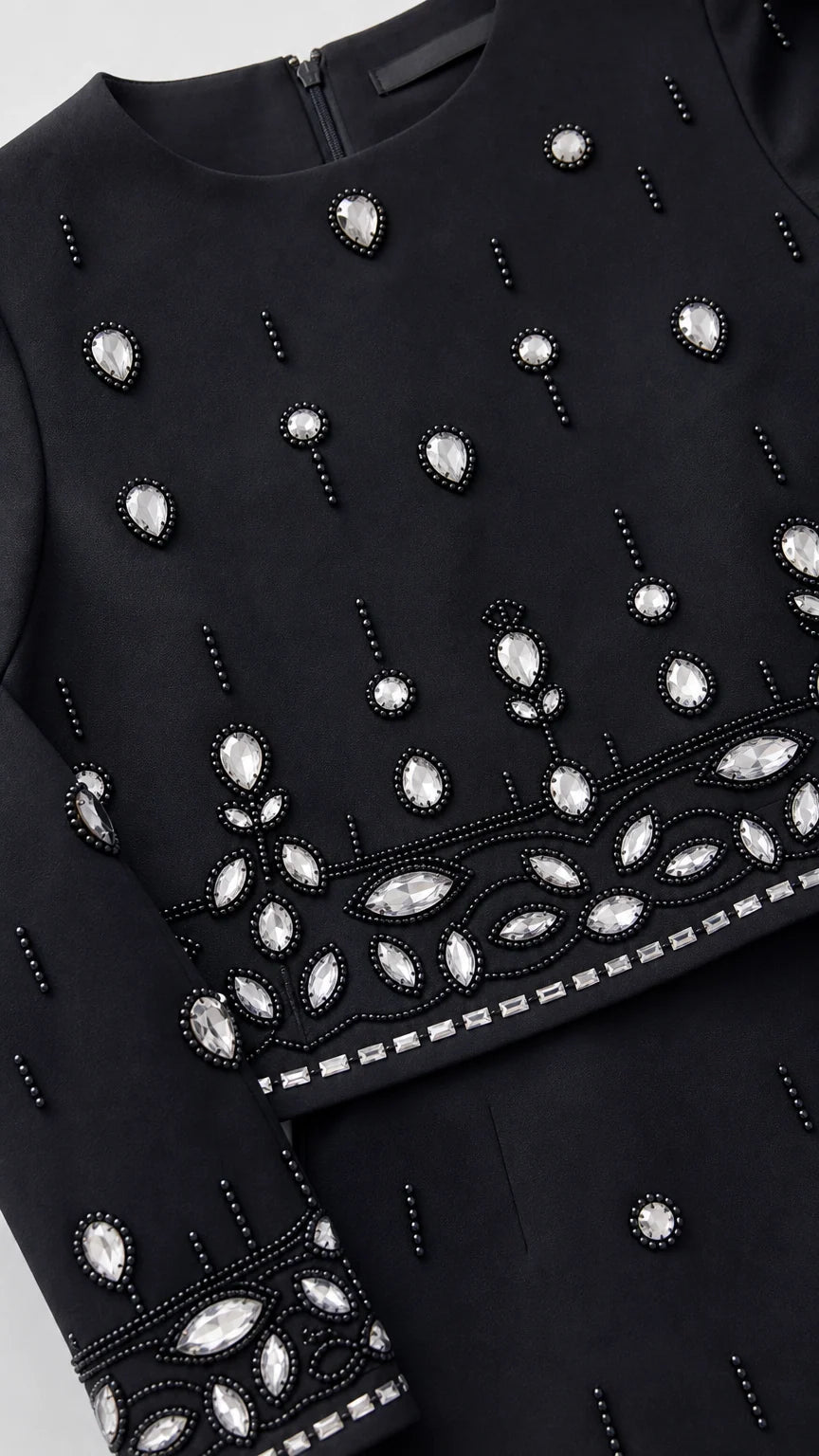 Close-up detail of sparkling crystal rhinestones and beadwork on neckline, hem, and sleeve cuff