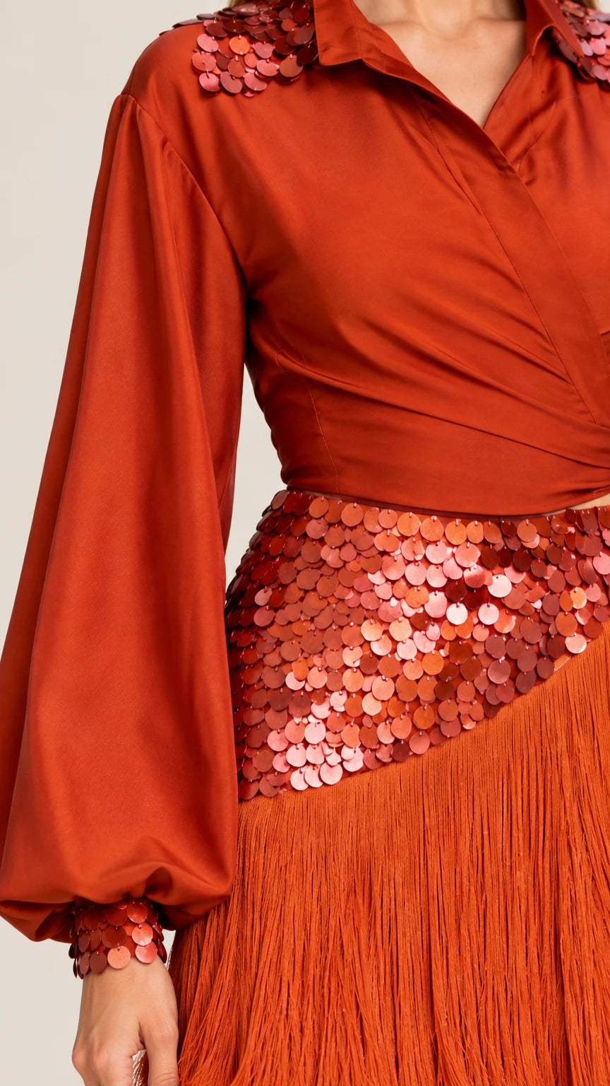 Close-up detail of rust orange satin wrap top with sequin shoulder and skirt embellishments