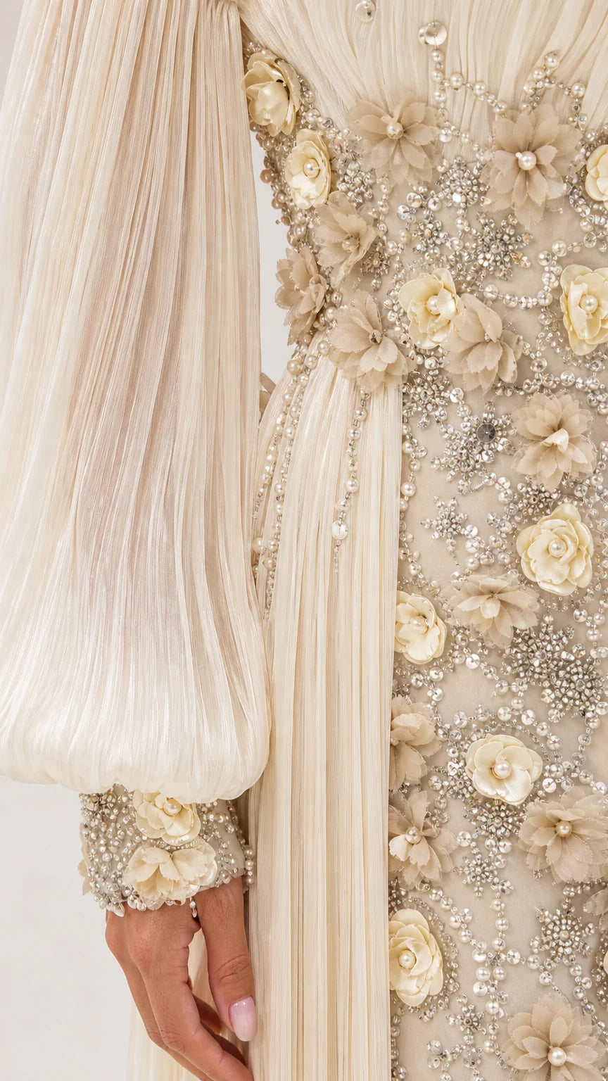 Close-up detail of champagne 3D floral appliqués, beadwork, and pleated sleeve cuff
