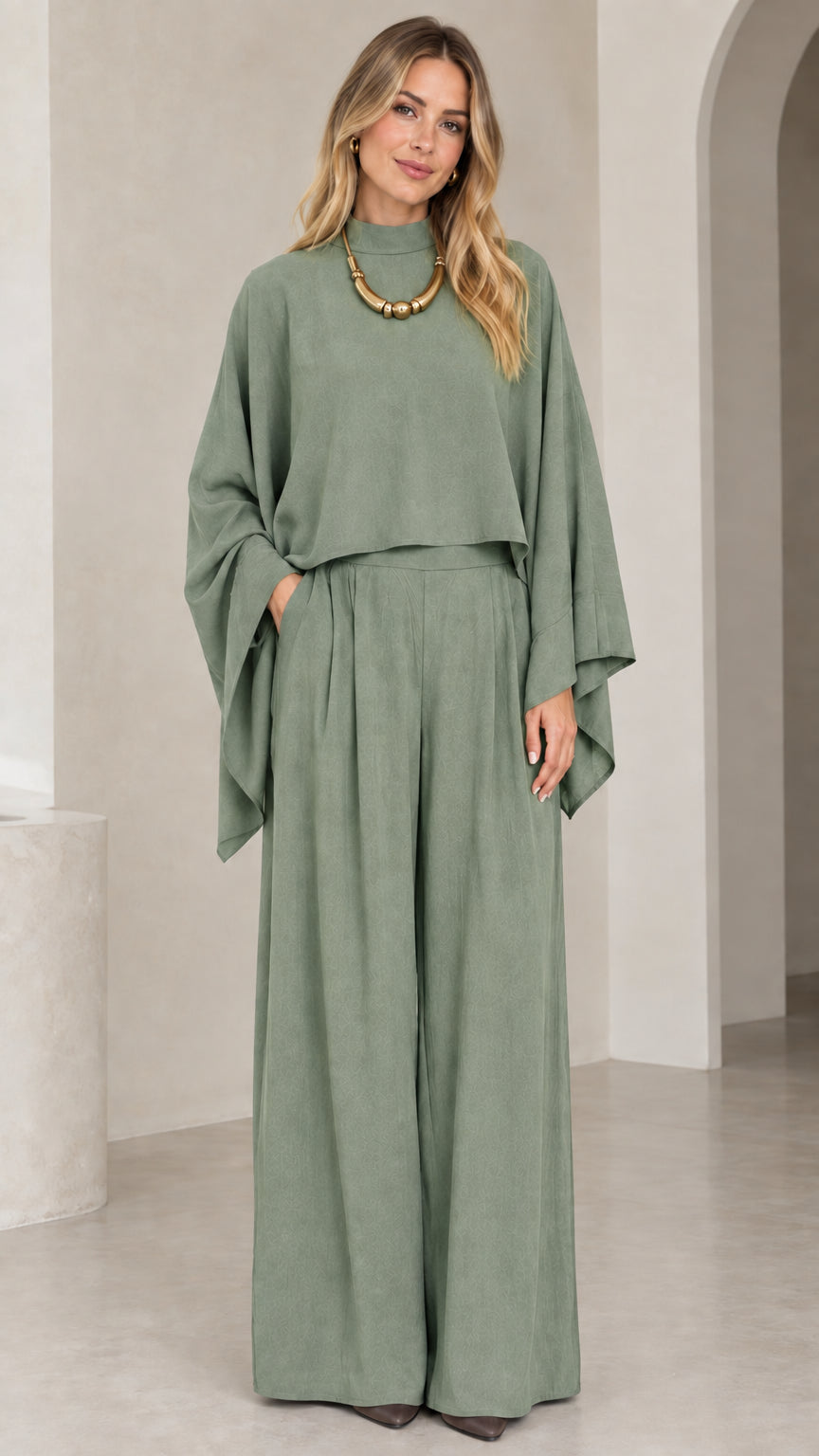 Full-length view of woman in sage green draped cape top and pleated wide leg pants set