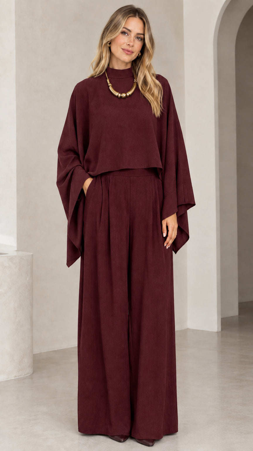 Full-length studio view of woman in burgundy wine cape top and wide leg two-piece set